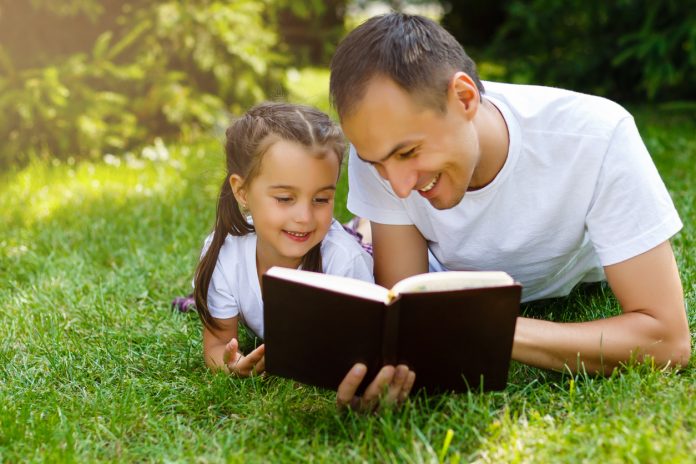 a young father with his little daughter reads the Bible
